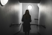 Black and white image of woman walking down some stairs with back to camera