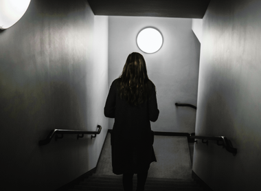 Black and white image of woman walking down some stairs with back to camera